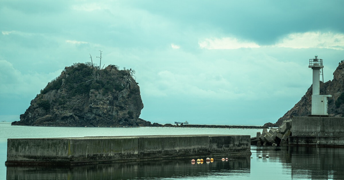 NIPPONIA 出雲鷺浦 漁師町 — 島根・出雲市鷺浦 · 防波堤と灯台、湾に浮かぶ岩のある日本海側の漁港