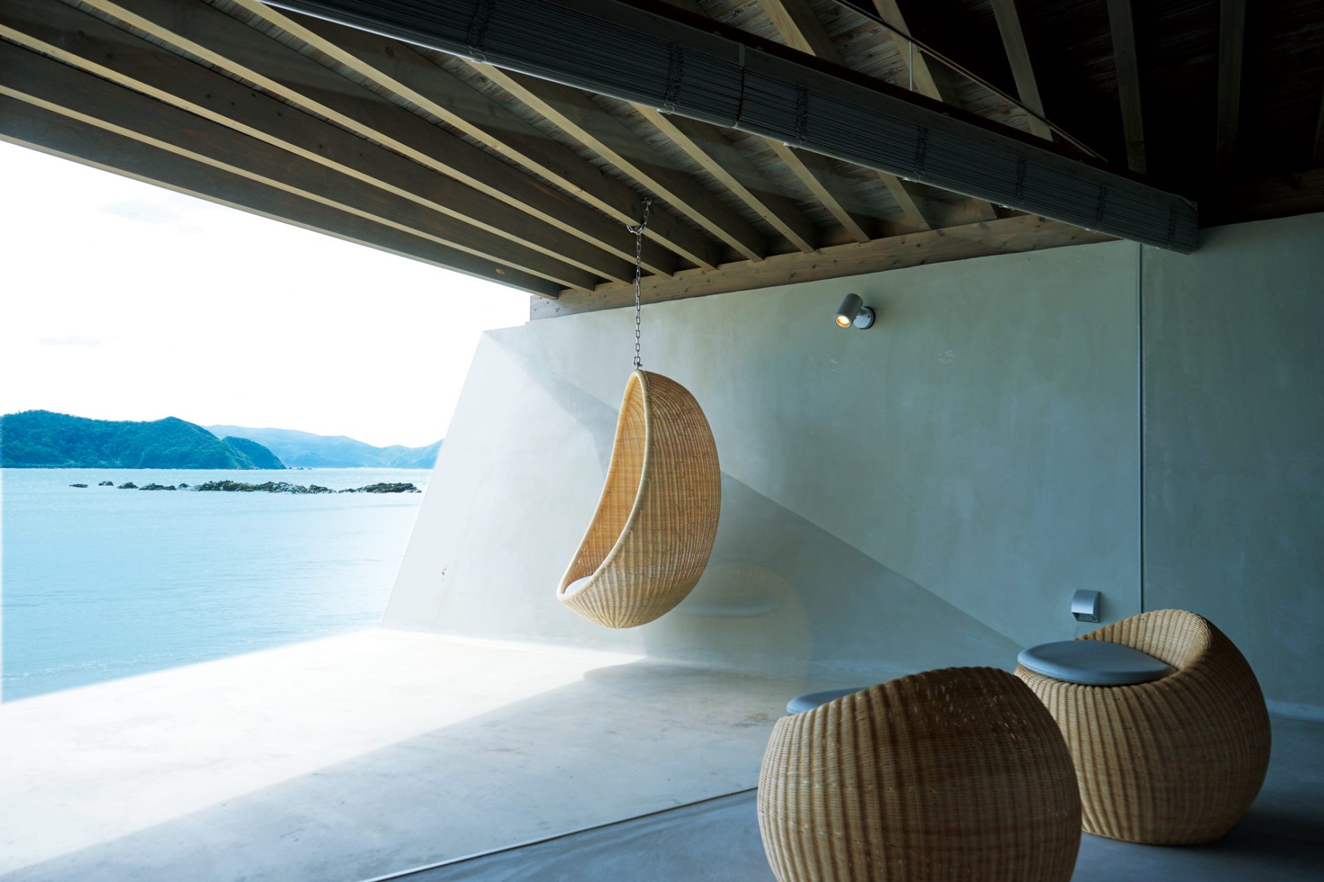 伝泊 The Beachfront MIJORA — 奄美大島・笠利 · 焼杉の屋根の下、海に開いたテラスとラタンチェア