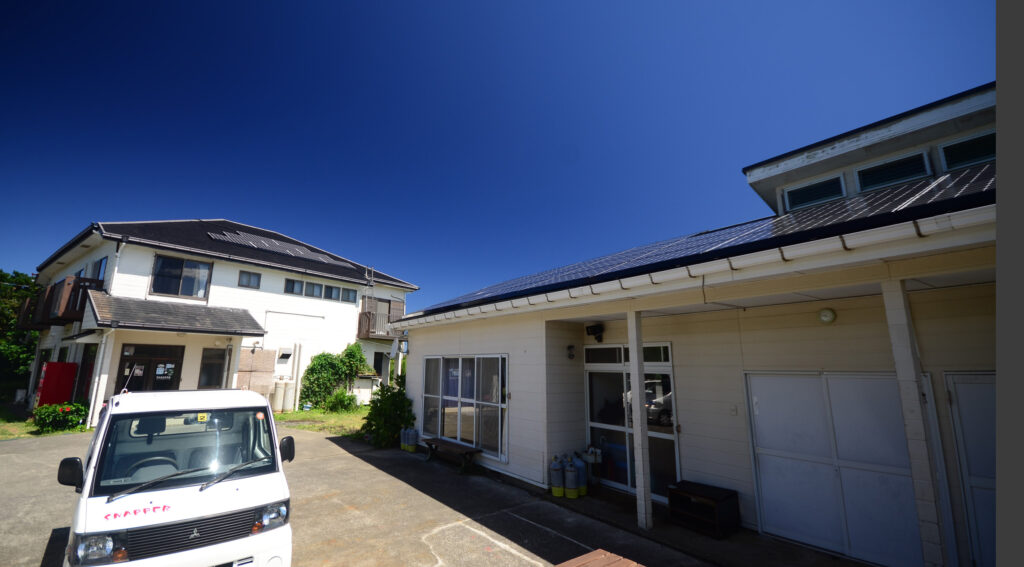 三宅島スナッパー — 三宅島・神着 · 抜けるような夏空の下、ダイビングとドルフィンスイムのガイドが営む白い宿
