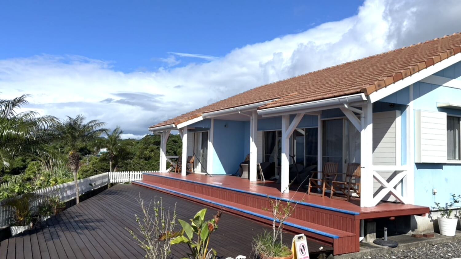 屋久島ペンション ルアナハウス — 屋久島町尾之間 · 椰子と広いウッドデッキを持つ水色の南国ペンション