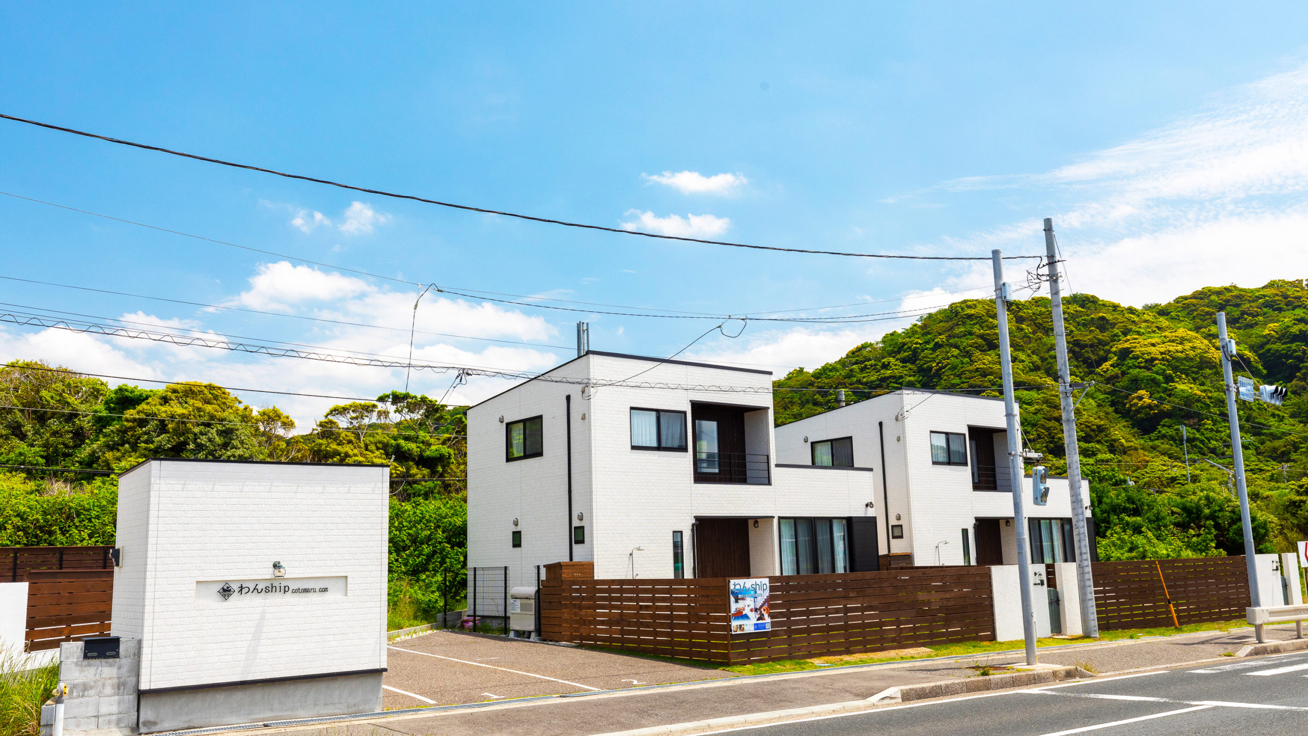 コトマル。わんship — 千葉県富津市金谷 · 内房なぎさライン沿いに立つ白い貸別荘の外観と背後の山肌