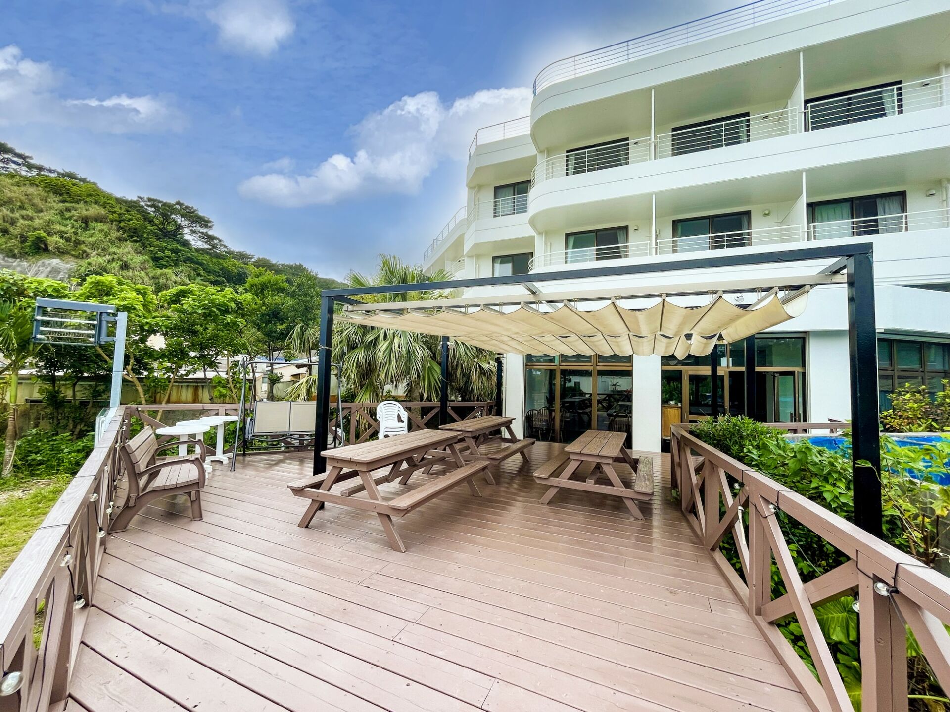 Kerama Blue Resort — 沖縄県座間味村・座間味島阿佐 · 亜熱帯の斜面に立つ白い本館とウッドデッキ