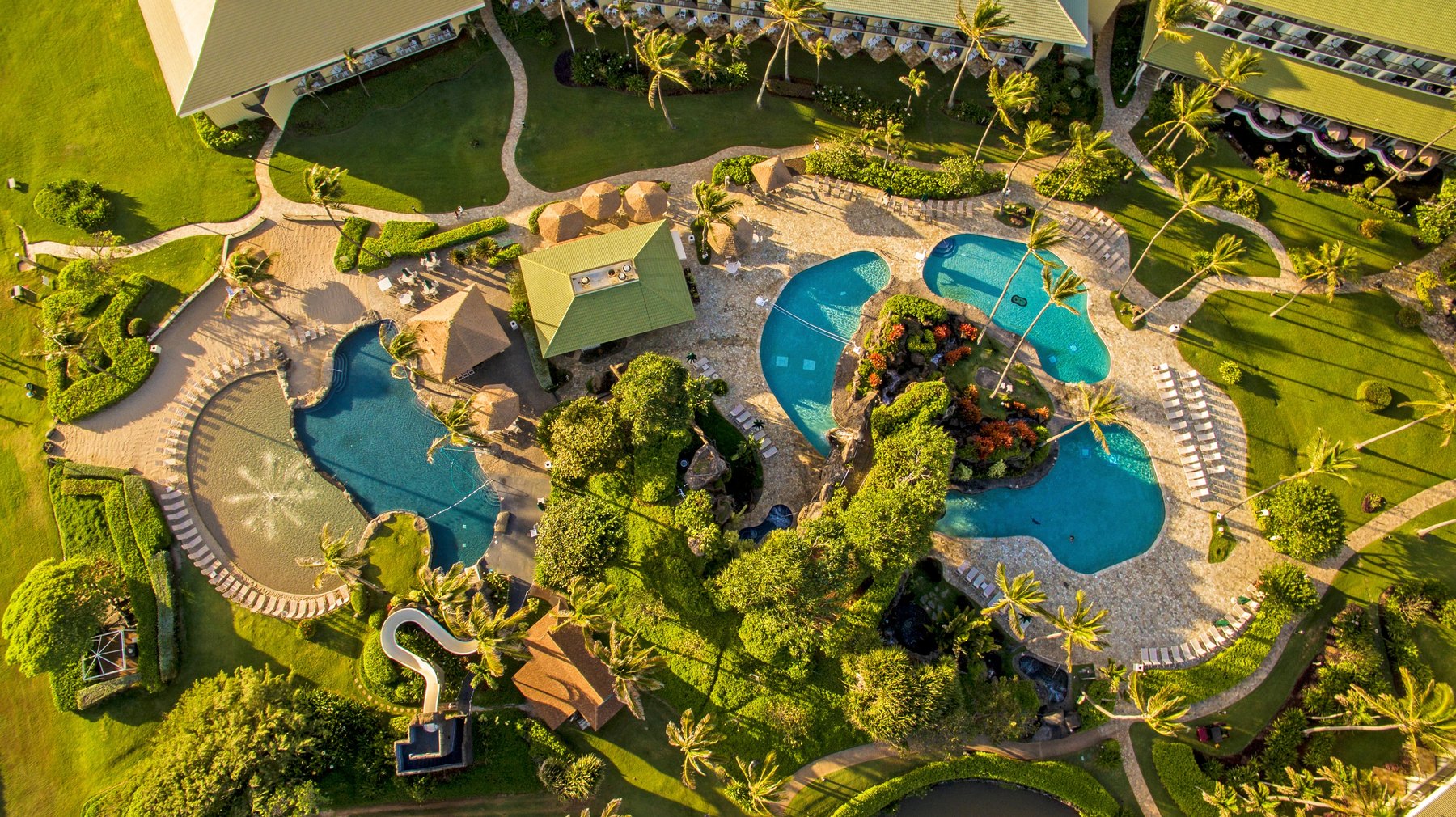 OUTRIGGER Kauaʻi Beach Resort & Spa — カウアイ島東海岸ヌコリイ · 芝と椰子に囲まれた四つの水面とスライダーを持つプール群を真上から
