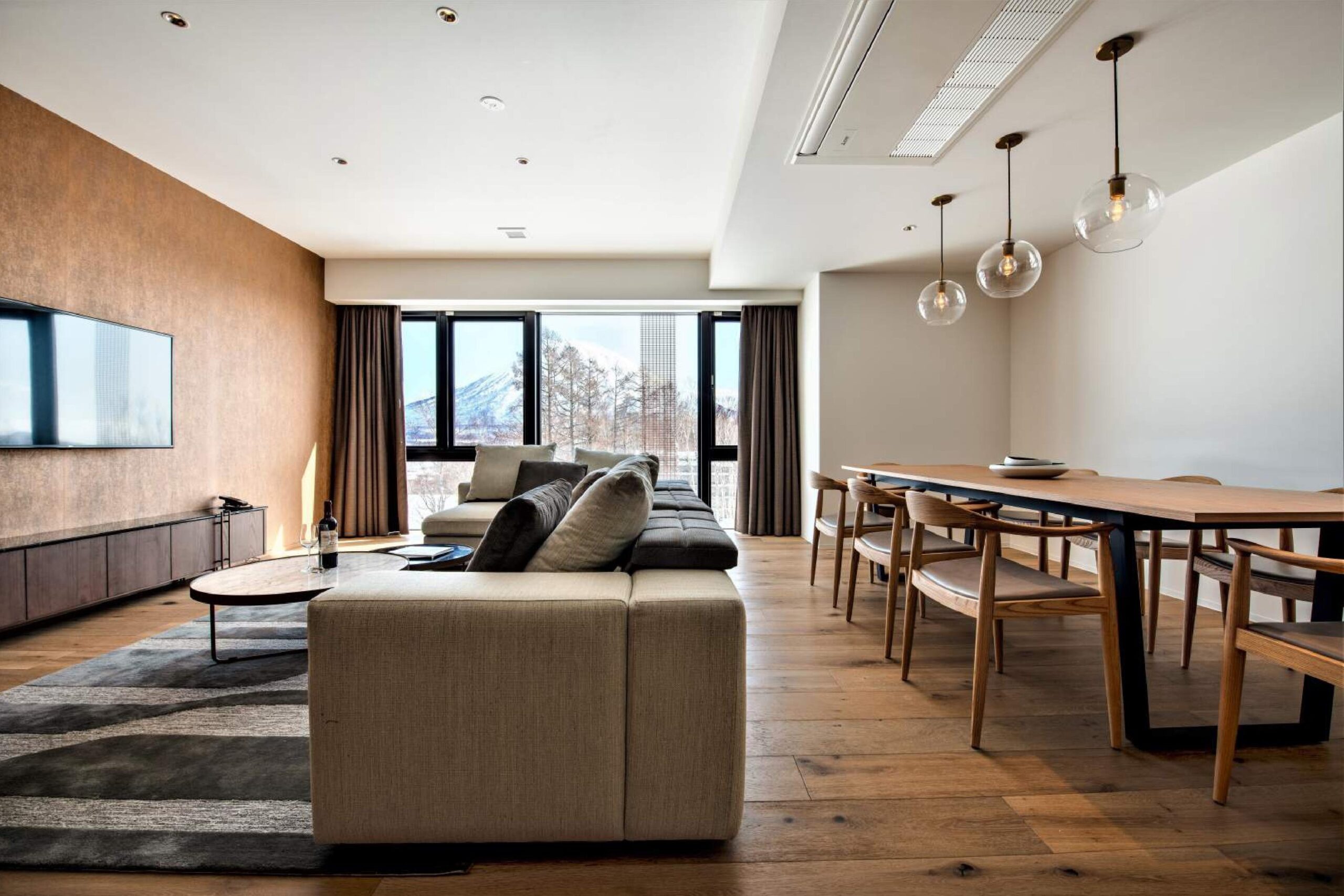 Intuition Niseko — 倶知安町ひらふ · 窓の向こうに雪の羊蹄山を望む3ベッドルームのリビング