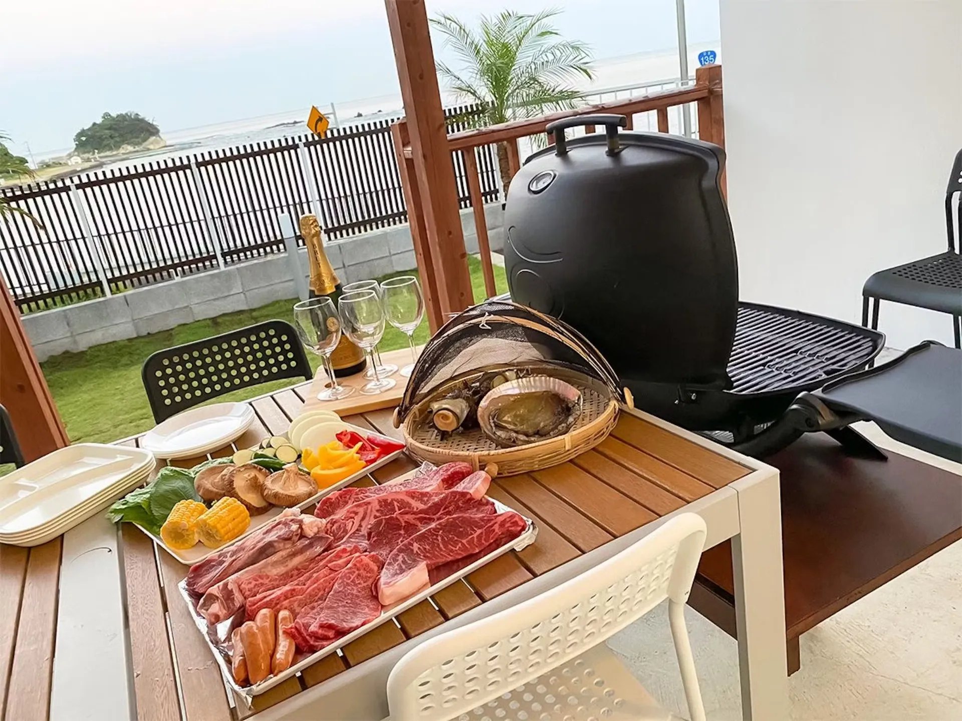 KRバーズヴィラ伊豆白浜リゾート — 下田市白浜 · 屋根付きテラスのBBQ席と、その先に見える白浜の海