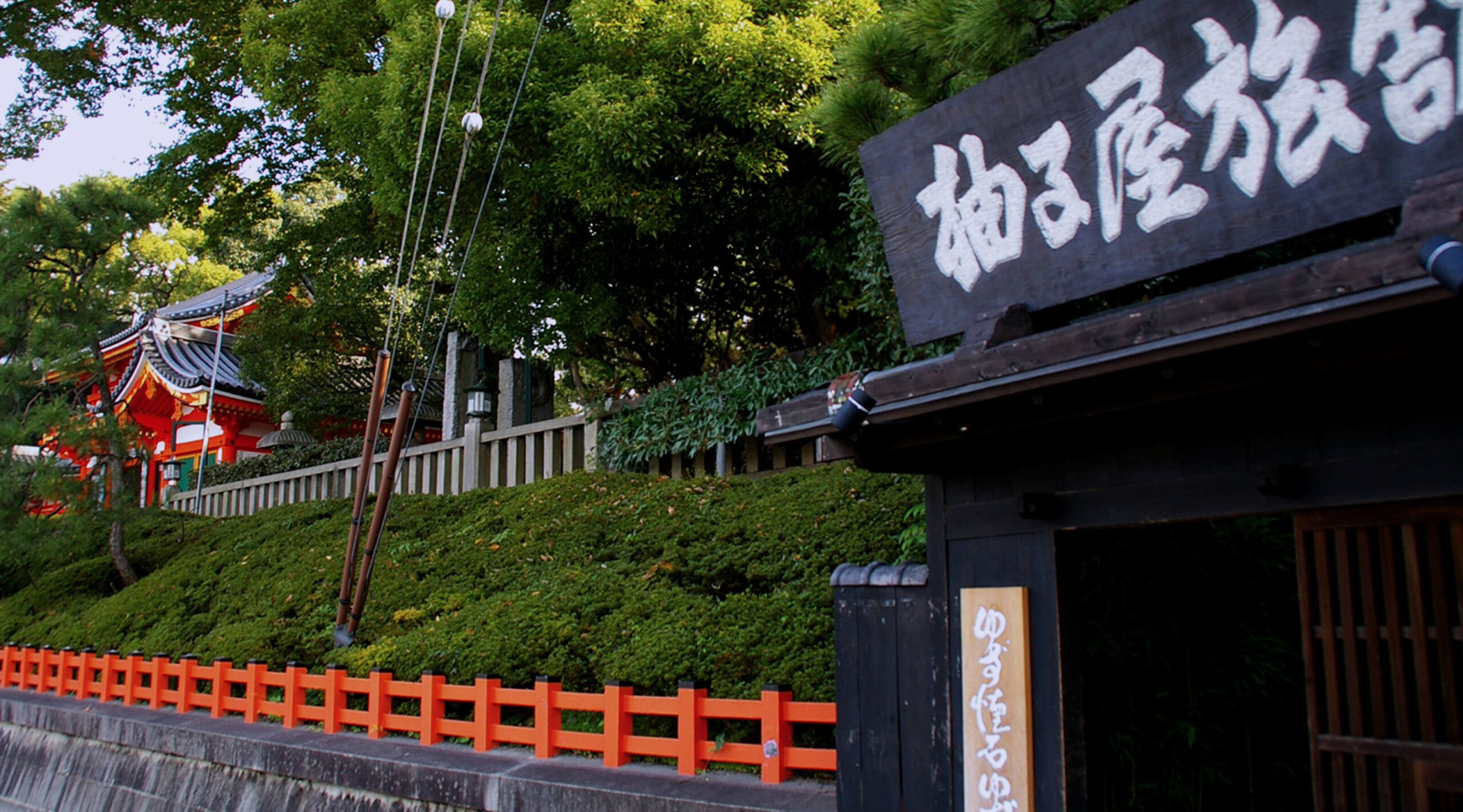 柚子屋旅館 — 京都・祇園 八坂神社南隣 · 朱塗りの西楼門を背にした、木の看板と石段の入口