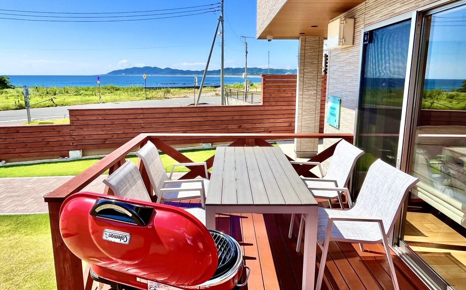 AIHAMA TERRACE — 館山市相浜 · 芝の庭に面したウッドデッキとBBQテーブル、奥に相浜の海