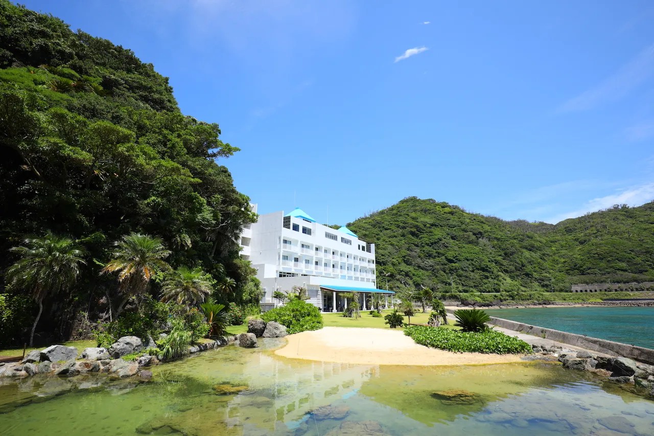 奄美山羊島ホテル — 奄美市名瀬大熊 · 名瀬湾の小島に建つ白いホテルと入り江の浜