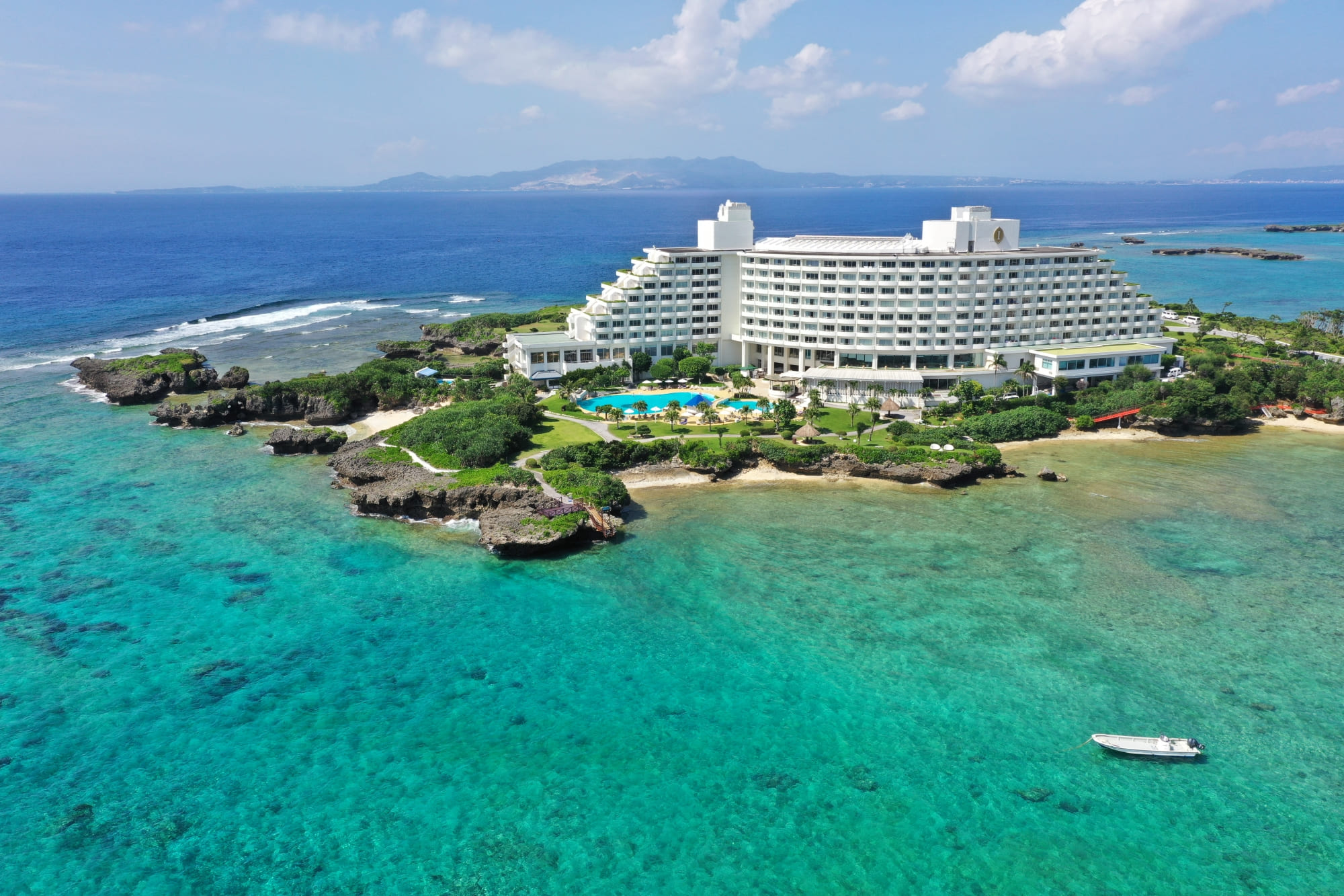 ANAインターコンチネンタル万座ビーチリゾート — 沖縄県恩納村 · 珊瑚礁の海に突き出た岬に建つホテル棟とビーチの空撮