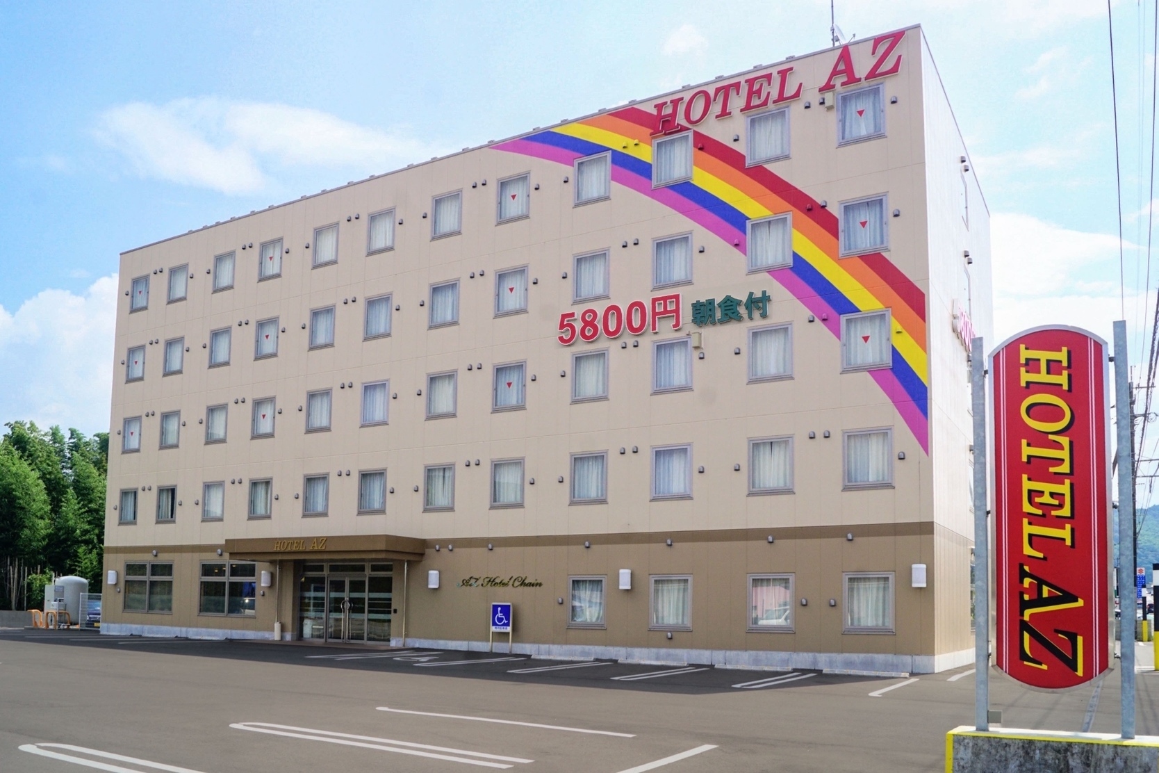 HOTEL AZ 宮崎えびの店 — 宮崎県えびの市杉水流 · 虹のラインが入った外観と広い駐車場