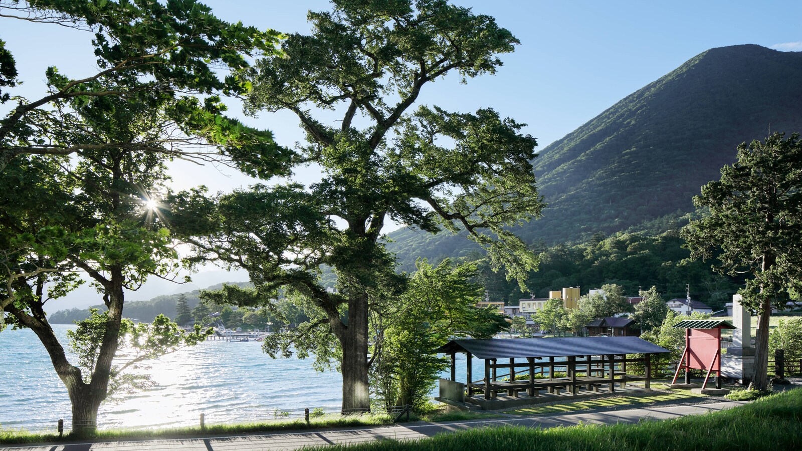 ザ・リッツ・カールトン日光 — 中禅寺湖の湖岸 · 木立の下に置かれたあずまやと、背後に立つ男体山