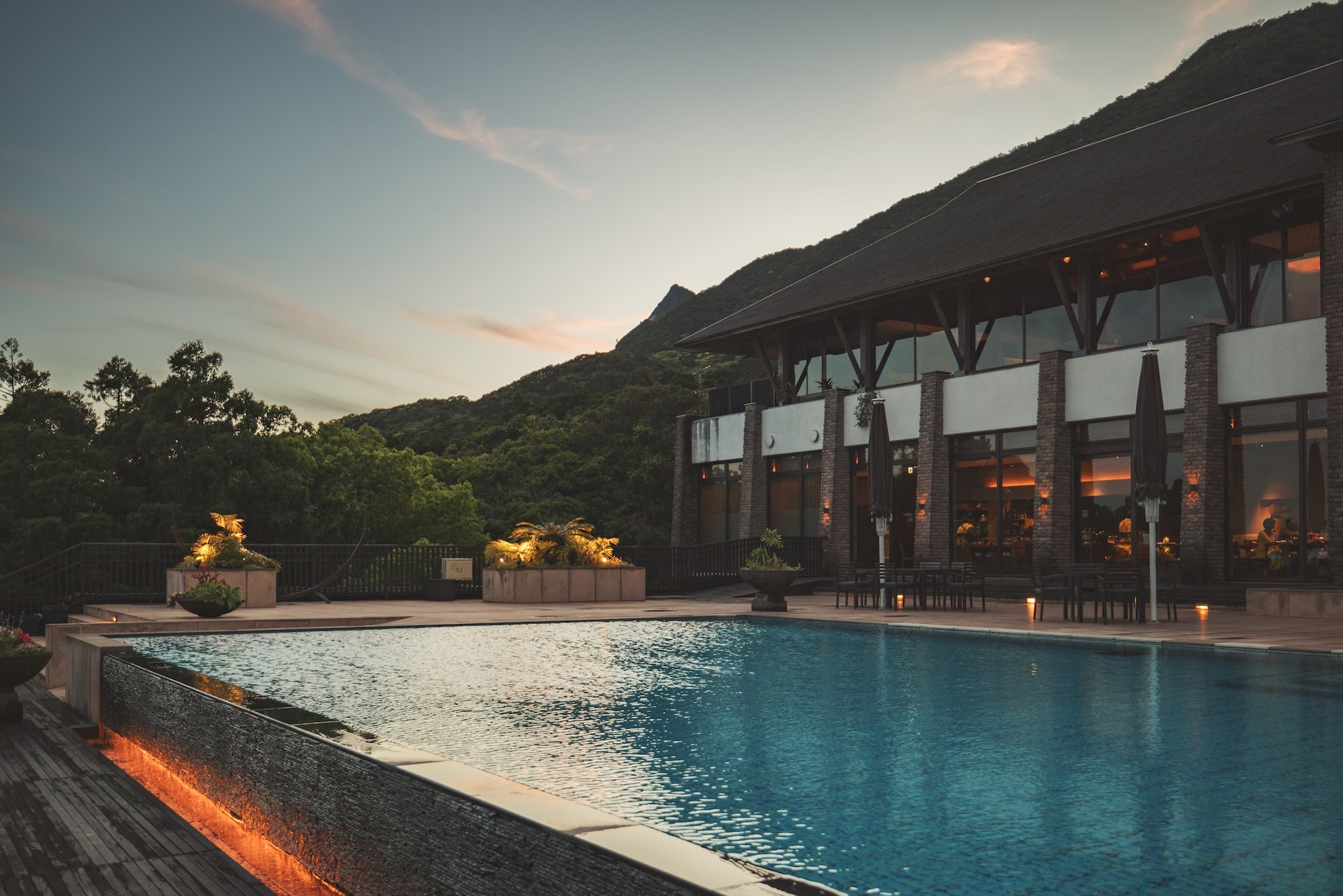 sankara hotel & spa 屋久島 — 屋久島・麦生 · 山を背にした夕暮れのプールとダイニング棟